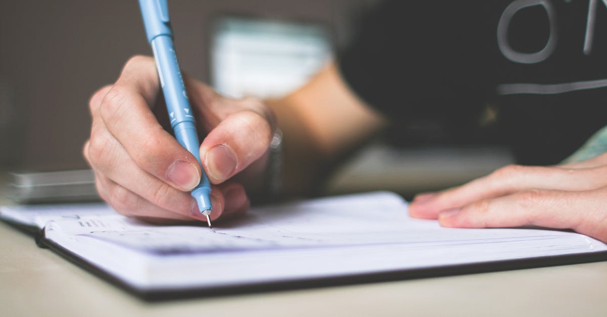 pexels-photo-210661-210661 Person Holding Blue Ballpoint Pen Writing in Notebook